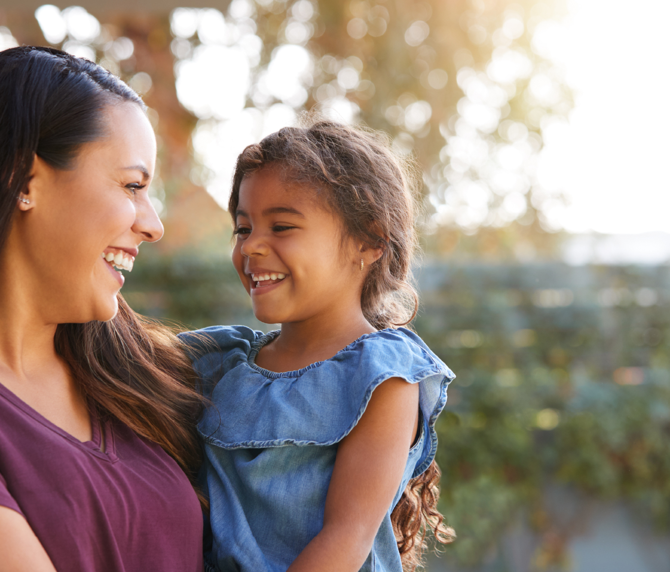 Smiling Hispanic mother holding daughter.